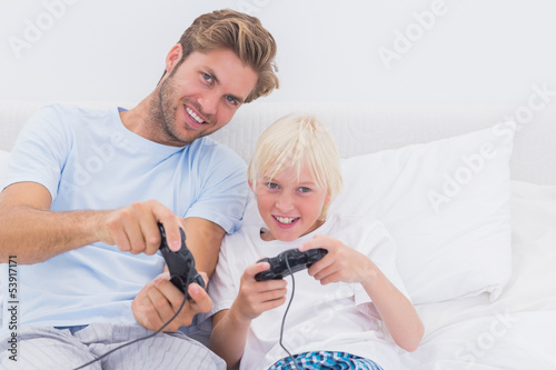 Photo: Cheerful father and son playing video games Cheerful father and son playing video games