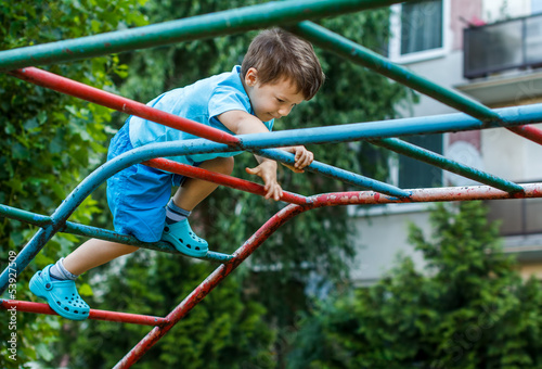 Photo: Little boy climbing on jungle gym without rope and helmet Little boy climbing on jungle gym without rope and helmet