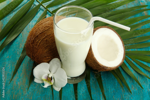 Photo: Coconuts with glass of milk, on blue wooden background Coconuts with glass of milk, on blue wooden background