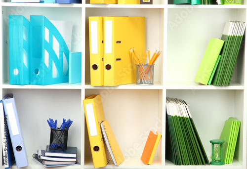 Photo: White office shelves with different stationery, close up White office shelves with different stationery, close up