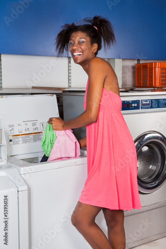 Photo: Woman Putting Clothes In Washing Machine Woman Putting Clothes In Washing Machine