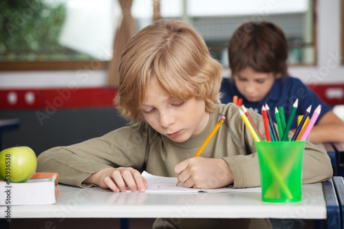Photo: Schoolboy Writing In Book At Desk Schoolboy Writing In Book At Desk