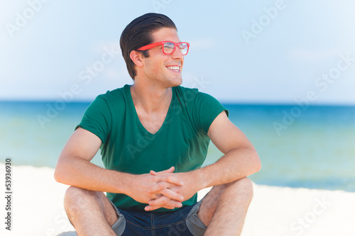 Photo: Handsome young man at beach background Handsome young man at beach background