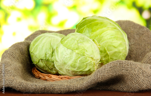 Photo: Green cabbage on wicker mat and sackcloth, on bright background Green cabbage on wicker mat and sackcloth, on bright background