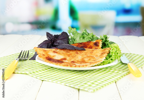 Photo: Tasty chebureks with fresh herbs on plate,on bright background Tasty chebureks with fresh herbs on plate,on bright background