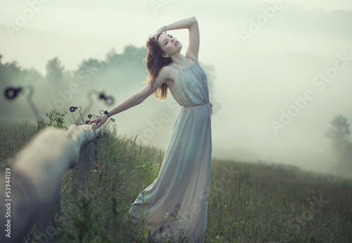 Photo: Tired brunette lady leaning against the fence Tired brunette lady leaning against the fence