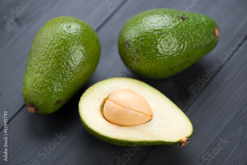 Photo: Ripe avocados on black wooden boards: whole and cut Ripe avocados on black wooden boards: whole and cut