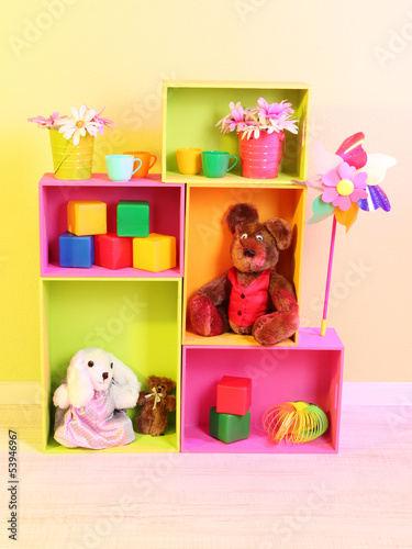 Photo: Bright shelves of different colors with toys on wall background Bright shelves of different colors with toys on wall background