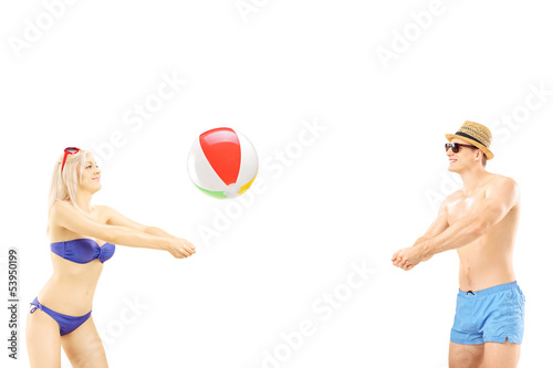 Photo: Young male and female in swimwear playing with a beach ball Young male and female in swimwear playing with a beach ball