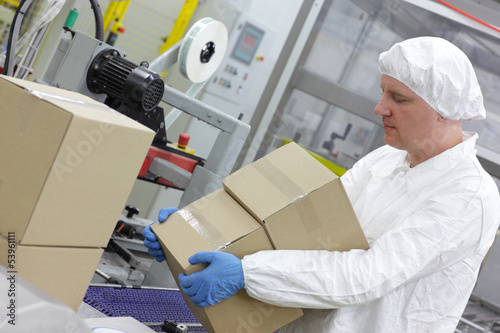 Photo: White male worker working on packing line in factory White male worker working on packing line in factory