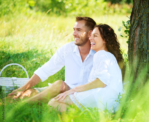 Photo: Young Couple Having Picnic in a Park. Happy Family Outdoor Young Couple Having Picnic in a Park. Happy Family Outdoor