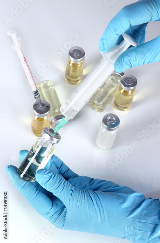 Photo: Medical bottles and syringes in hand on gray background Medical bottles and syringes in hand on gray background
