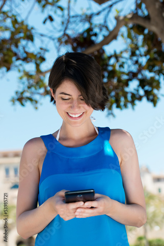 Photo: frau schaut draußen auf ihr handy frau schaut draußen auf ihr handy