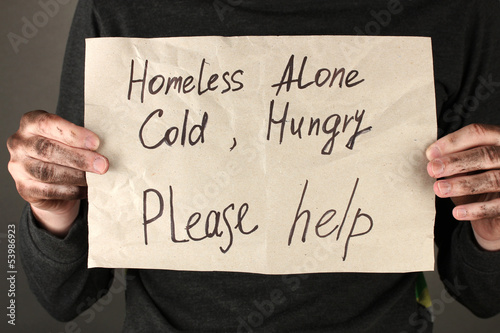 Photo: homeless man asks for help, on black background close-up homeless man asks for help, on black background close-up