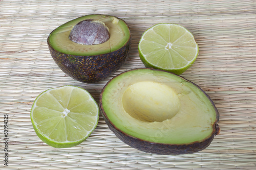 Photo: An avocado and lime cut in half on a straw mat. An avocado and lime cut in half on a straw mat.
