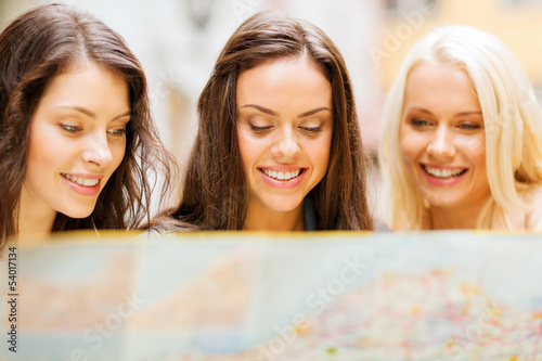 Photo: beautiful girls looking into tourist map in city beautiful girls looking into tourist map in city