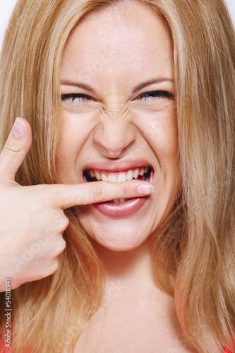 Photo: Happy blonde woman biting his finger. Isolated on white. Happy blonde woman biting his finger. Isolated on white.