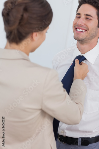 Photo: Woman helping her smiling husband to tie his tie Woman helping her smiling husband to tie his tie