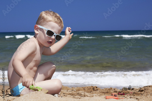 Photo: child plays on the beach in sand child plays on the beach in sand