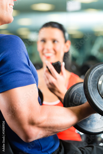 Photo: Trainer und Mann mit Hanteln im Fitness studio Trainer und Mann mit Hanteln im Fitness studio