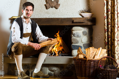 Photo: Junger Mann in Almhütte in den Alpen am Kamin Junger Mann in Almhütte in den Alpen am Kamin