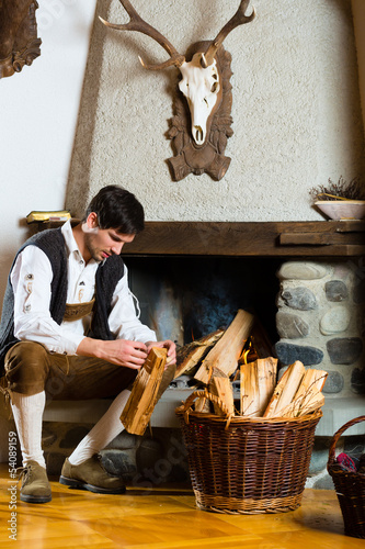 Photo: Junger Mann in Almhütte in den Alpen am Kamin Junger Mann in Almhütte in den Alpen am Kamin