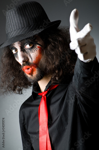 Photo: Joker personification with man in dark room Joker personification with man in dark room