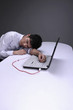 Photo: Businessman transferring blood from his hand to laptop through IV drip tube, head lying on the table Businessman transferring blood from his hand to laptop through IV drip tube, head lying on the table