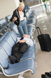 Photo: Businessman asleep on seat in airport lounge, businesswoman standing over him pointing finger Businessman asleep on seat in airport lounge, businesswoman standing over him pointing finger
