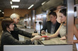 Photo: Airline check-in attendant returning passports to business people at the airport check-in counter Airline check-in attendant returning passports to business people at the airport check-in counter