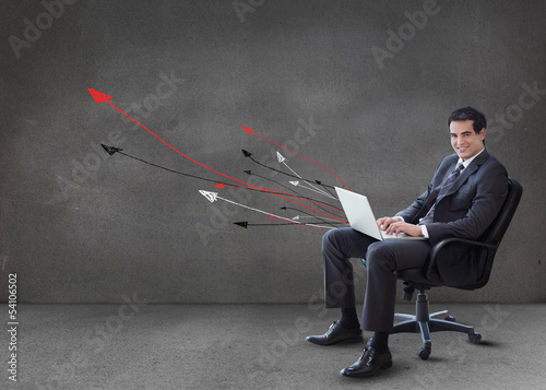 Photo: Businessman using his laptop arrows coming from it Businessman using his laptop arrows coming from it