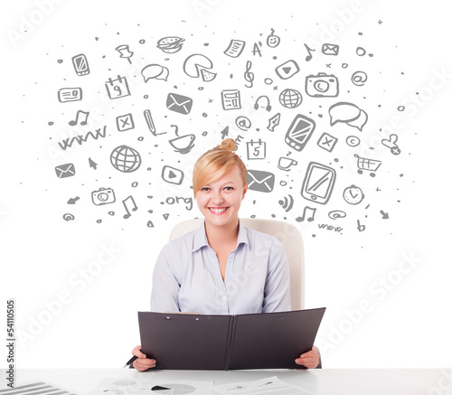 Photo: Young businesswoman with all kind of hand-drawn media icons in b Young businesswoman with all kind of hand-drawn media icons in b