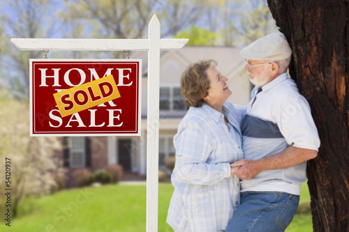 Photo: Sold Real Estate Sign with Senior Couple in Front of House Sold Real Estate Sign with Senior Couple in Front of House