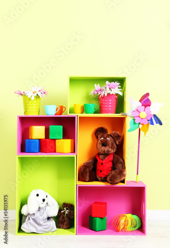 Photo: Bright shelves of different colors with toys on wall background Bright shelves of different colors with toys on wall background