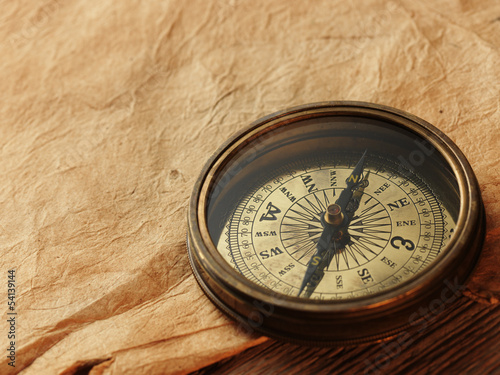 Photo: old compass on vintage background old compass on vintage background