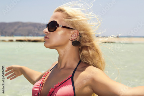 Photo: Beautiful blond woman in sunglasses on beach.paradise island Beautiful blond woman in sunglasses on beach.paradise island