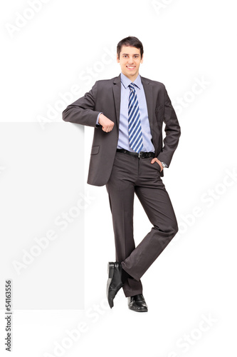 Photo: Full length portrait of a young businessman posing on a panel Full length portrait of a young businessman posing on a panel