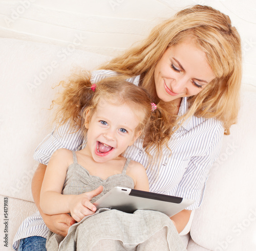 Photo: Mother and daughter wiht tablet at sofa Mother and daughter wiht tablet at sofa