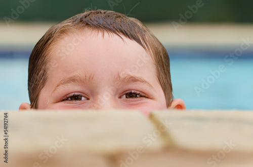 Photo: Portrait of child peeking over edge of pool while swimming Portrait of child peeking over edge of pool while swimming