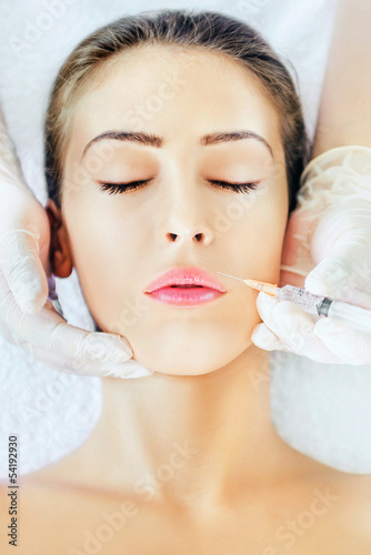 Photo: Young woman receiving botox injection in lips Young woman receiving botox injection in lips