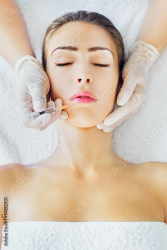 Photo: Young woman receiving botox injection in lips Young woman receiving botox injection in lips