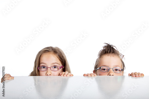 Photo: Kinder blicken neugierig über den Tisch Kinder blicken neugierig über den Tisch