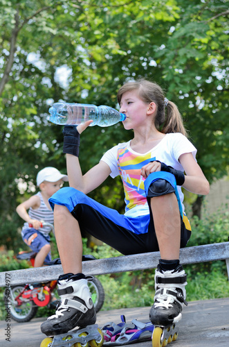 Photo: Girl pausing for a drink while roller skating Girl pausing for a drink while roller skating