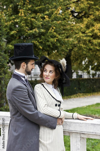 Photo: Old-fashioned dressed couple in the park in love Old-fashioned dressed couple in the park in love