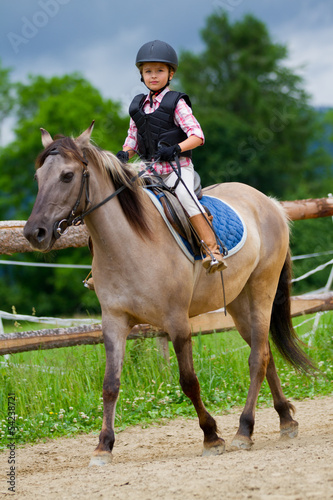 Photo: Horse riding - lovely girl is riding on a horse Horse riding - lovely girl is riding on a horse