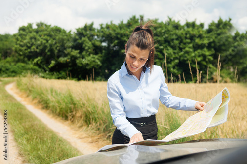 Photo: Lost woman standing outside of her car with a map Lost woman standing outside of her car with a map