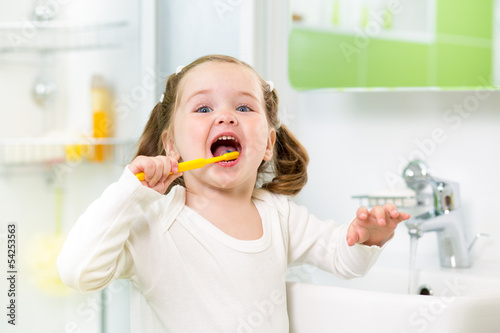 Photo: kid girl brushing teeth in bathroom kid girl brushing teeth in bathroom
