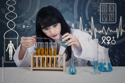 Photo: Attractive scientist examining liquid on digital Attractive scientist examining liquid on digital