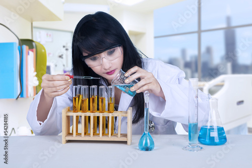 Photo: Beautiful scientist pouring liquid at lab Beautiful scientist pouring liquid at lab