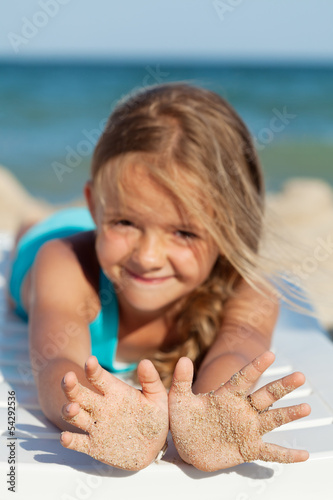 Photo: Happy little girl with sandy hands on the beach Happy little girl with sandy hands on the beach